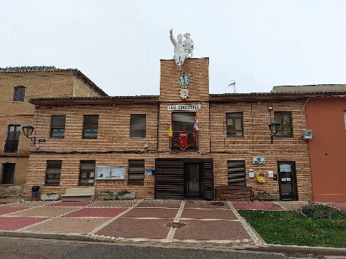 Town hall building with statue and flags in Husillos, Palencia.