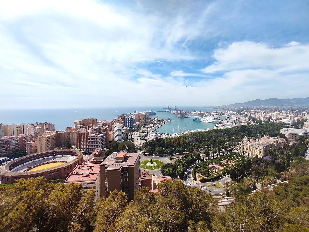 Luftaufnahme von Málaga mit Hafen, Stadt und Meer unter blauem Himmel.