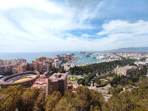 Luftaufnahme von Málaga mit Hafen, Stadt und Meer unter blauem Himmel.