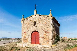 Small stone chapel with red door and cross on top in Used, Zaragoza.