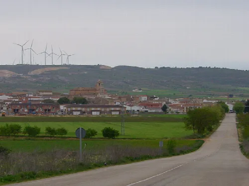 Ländliche Landschaft mit Stadt und Windkraftanlagen auf Hügeln.