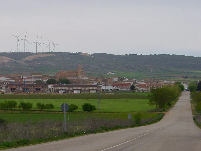 Ländliche Landschaft mit Stadt und Windkraftanlagen auf Hügeln.