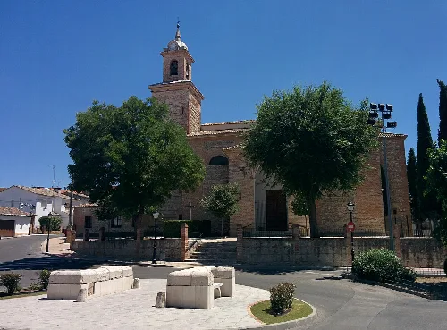 Kirche Unserer Lieben Frau der Himmelfahrt in Esquivias, Toledo, mit Bäumen und Platz davor.