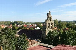 Iglesia de El Salvador en Castrocalbón, con campanario y casas rurales.