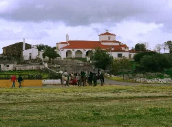 Virgin of the Encinar chapel in Ceclavín, Cáceres, with people and horses in the foreground.