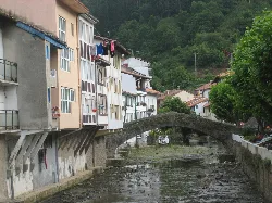 Häuser am Fluss mit einer römischen Brücke in Ea, Vizcaya.