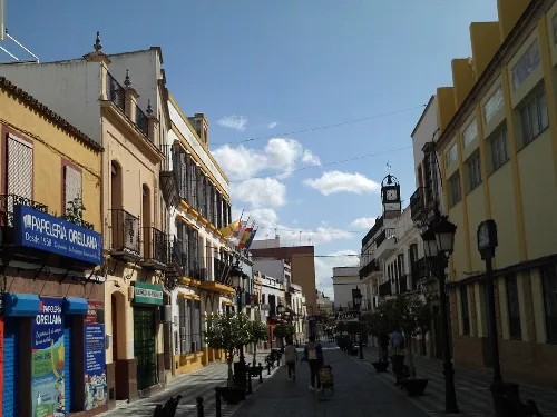 Straße mit Gebäuden, Geschäften und Laternen in Coria del Río.