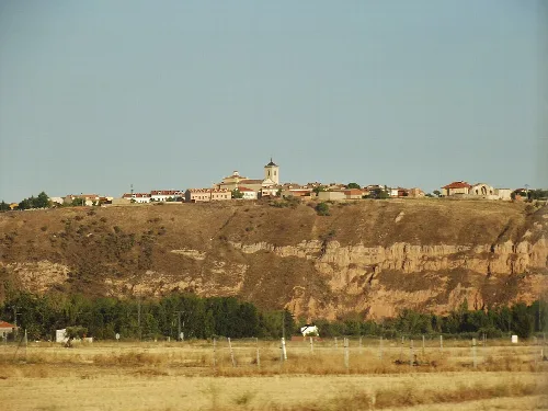 View of Uceda, Guadalajara, with houses and a building on the hilltop.