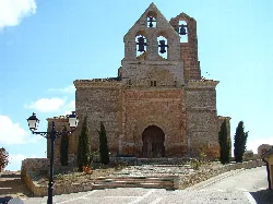 Mudéjar-Kirche San Andrés in Aguilar de Campos mit Treppe und Bäumen.