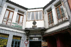 Balkon mit Fenstern und einer Plakette an der Fassade eines Gebäudes in Tineo.