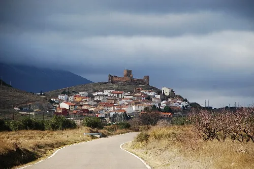 Village with castle on the hill and cloudy sky.