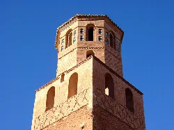 Kirchturm in Trasobares mit Bogenfenstern und blauem Himmel.