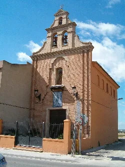 Brick chapel facade with bell tower and two lamps at the entrance.