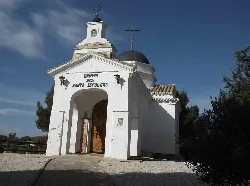Small white chapel with cross on the dome and arched entrance in Híjar.