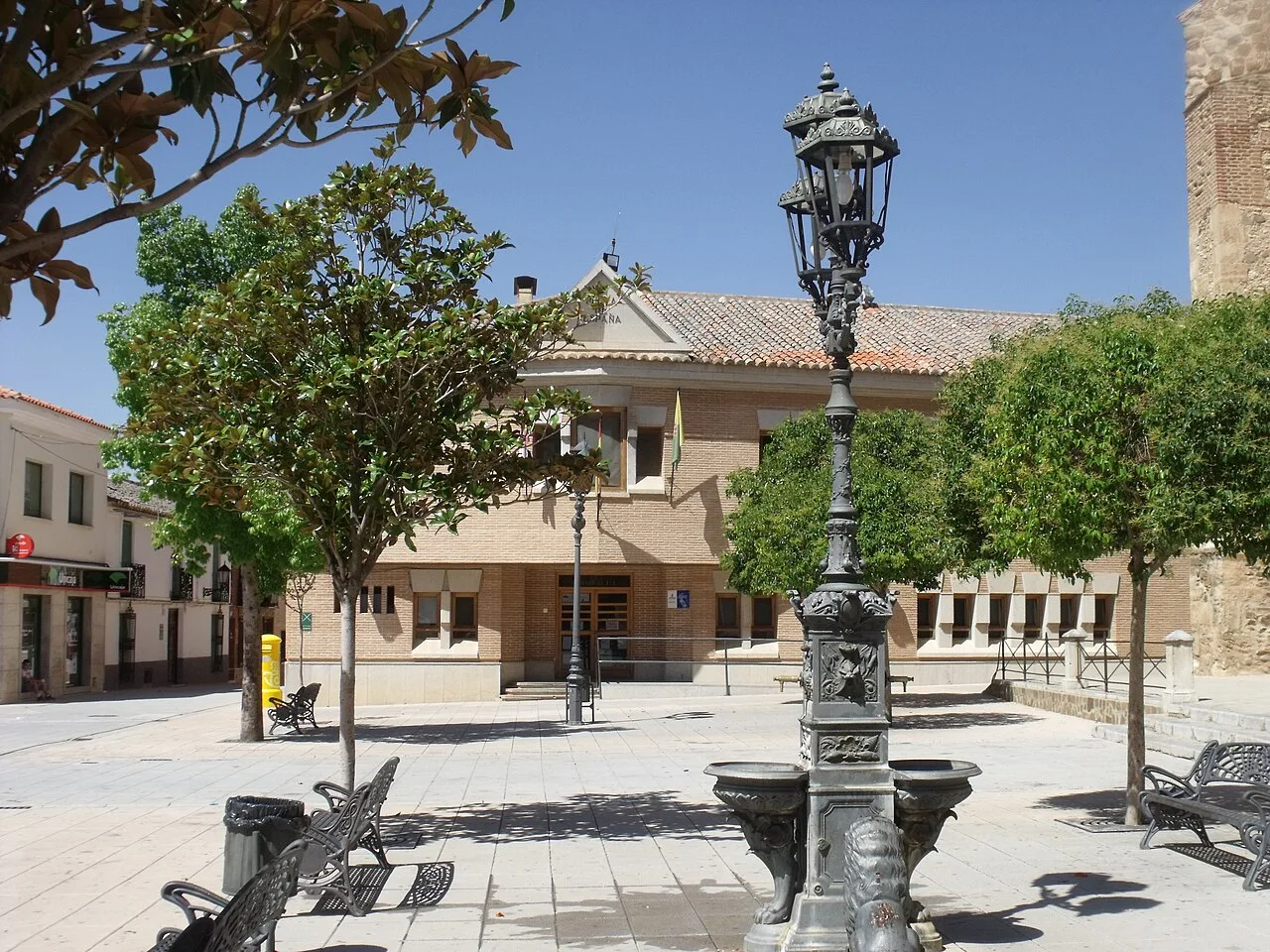 Plaza con ayuntamiento, árboles, bancos y farolas en Torrenueva