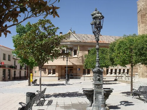 Plaza con ayuntamiento, árboles, bancos y farolas en Torrenueva