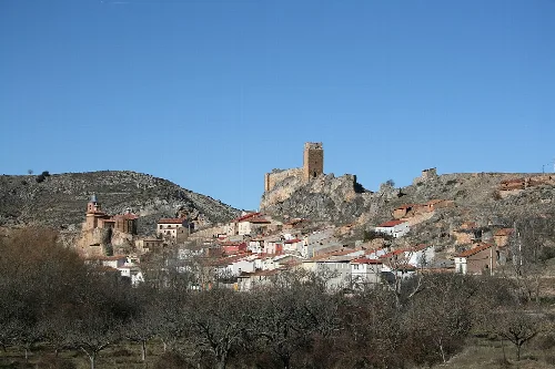 Panoramic view of Bijuesca with castle on the hill and houses on the slope.