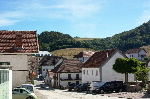 Weiße Häuser mit Ziegeldächern in Garralda, Navarra, mit Bergen im Hintergrund.