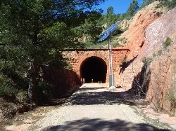 Túnel en la vía verde con paneles solares y vegetación a los lados