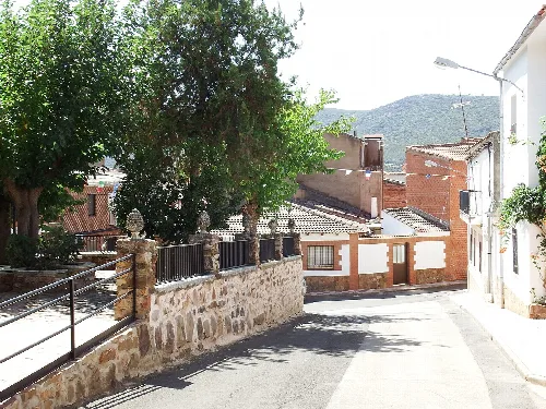 Enge Straße mit Häusern und Bäumen in Alcoba de los Montes.