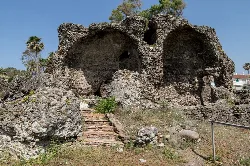 Ruinen der römischen Thermen mit Steinstufen und Vegetation.