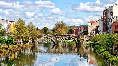 Steinbrücke über den Fluss Cabe mit Gebäuden und Bäumen an den Seiten.