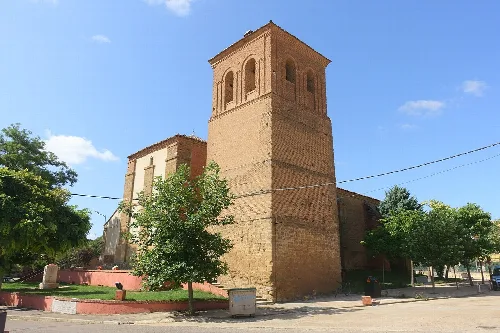 Torre de ladrillo de la iglesia y árboles en La Unión de Campos.