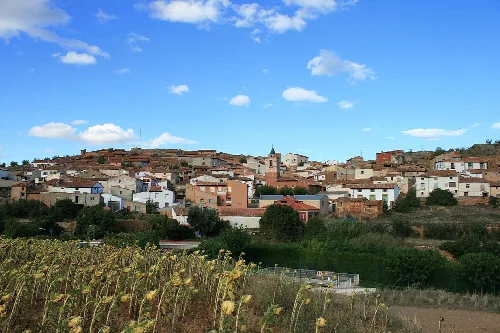 Panoramic view of Castejón de Alarba with white houses and field in foreground.