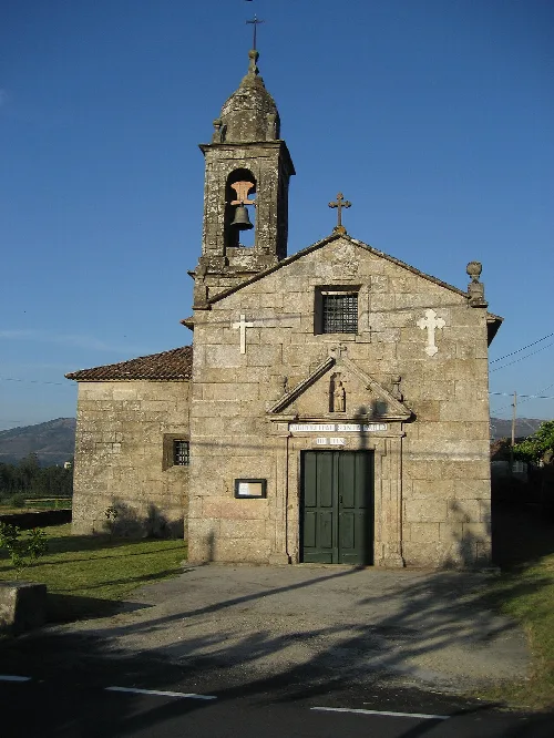 Steinige Kirche mit Glockenturm und Kreuz an der Fassade in Rois, La Coruña.
