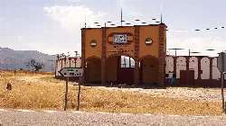 Plaza de toros de color naranja con arcos y cartel en la entrada en Zarza de Granadilla.