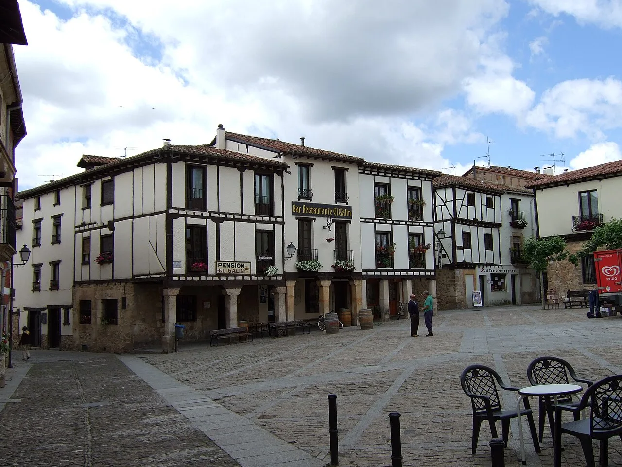 Plaza mayor de Covarrubias con casas blancas y madera, en un día nublado.
