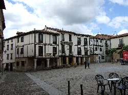 Plaza mayor de Covarrubias con casas blancas y madera, en un día nublado.