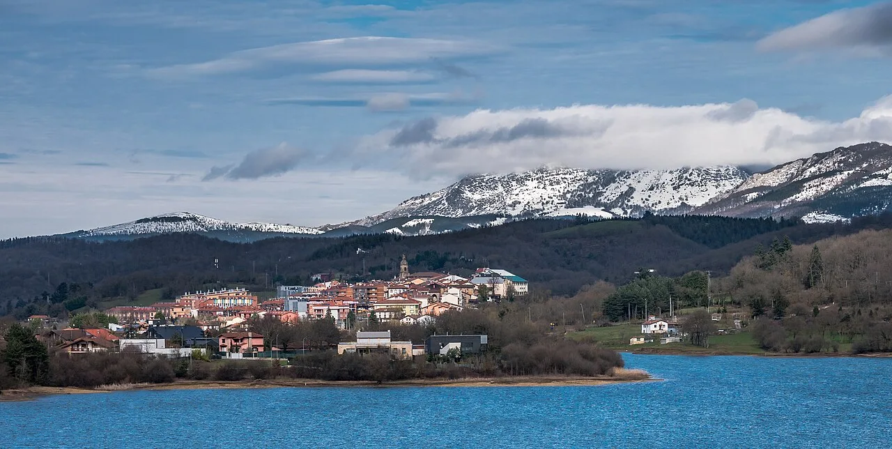 Vista del pueblo de Legutiano junto al embalse Urrunaga y montañas nevadas.