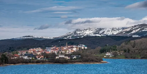 Blick auf Legutiano und den Urrunaga-Stausee mit schneebedeckten Bergen.