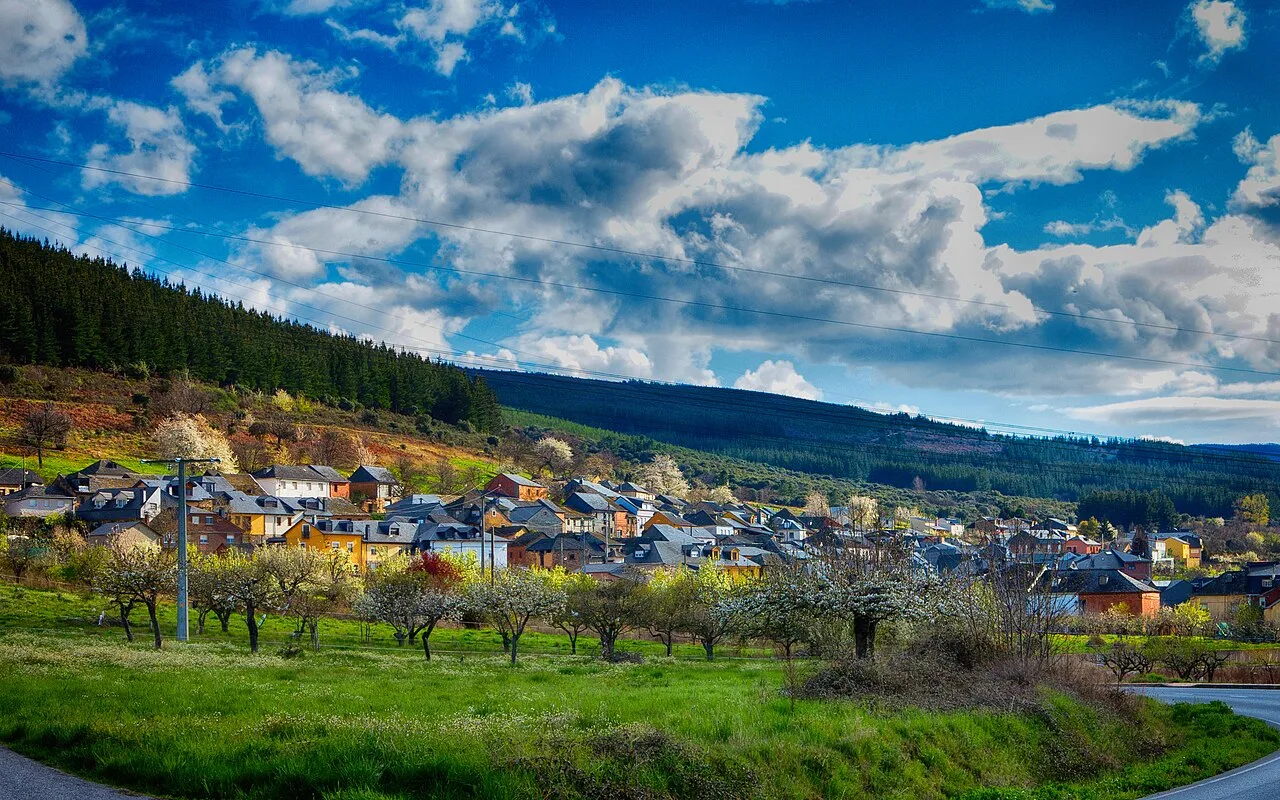 Paisaje de Castropodame con casas, árboles y cielo nublado.