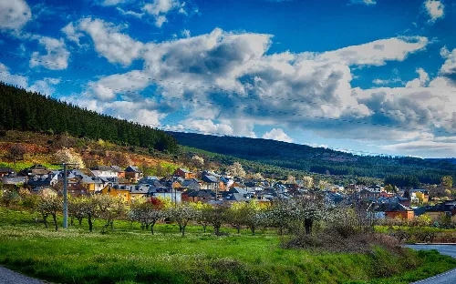 Landschaft von Castropodame mit Häusern, Bäumen und bewölktem Himmel.