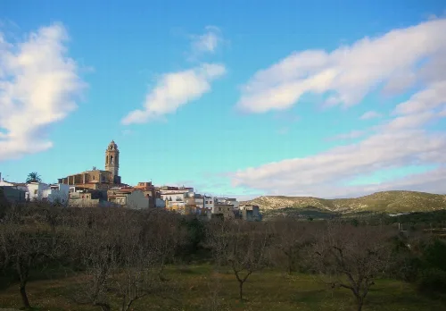 Blick auf das Dorf Traiguera mit Kirche und weißen Häusern unter blauem Himmel.