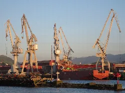 Shipyard cranes in Sestao by the river with mountains.