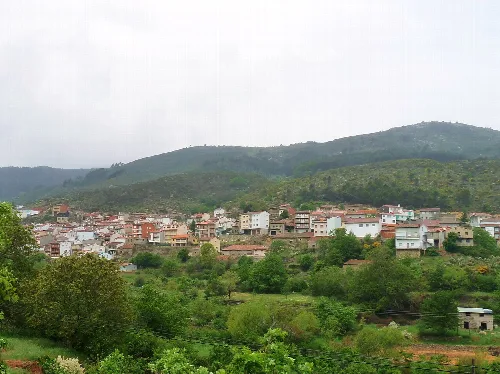 Landschaft von Serranillos mit Häusern und grünen Hügeln.