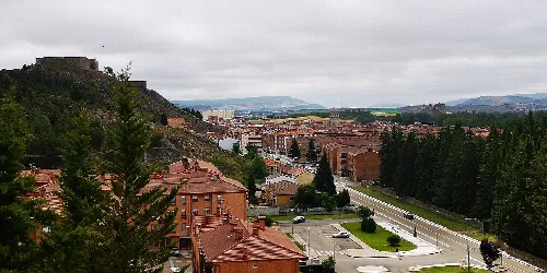 Houses and park in Aguilar de Campoo with town and hills in the background.