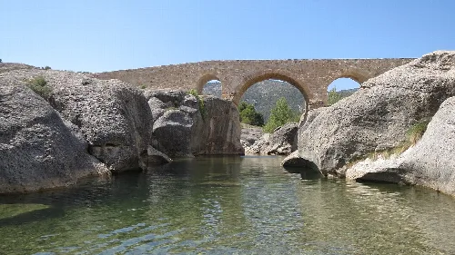 Bergantes-Fluss mit einer alten Steinbrücke darüber in La Ginebrosa.