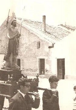 Procesión con la imagen de San Juan Bautista y personas en la calle en 1945.