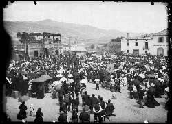 Menschenmenge auf dem Platz in Jaca mit Regenschirmen und einer Bühne im Hintergrund.