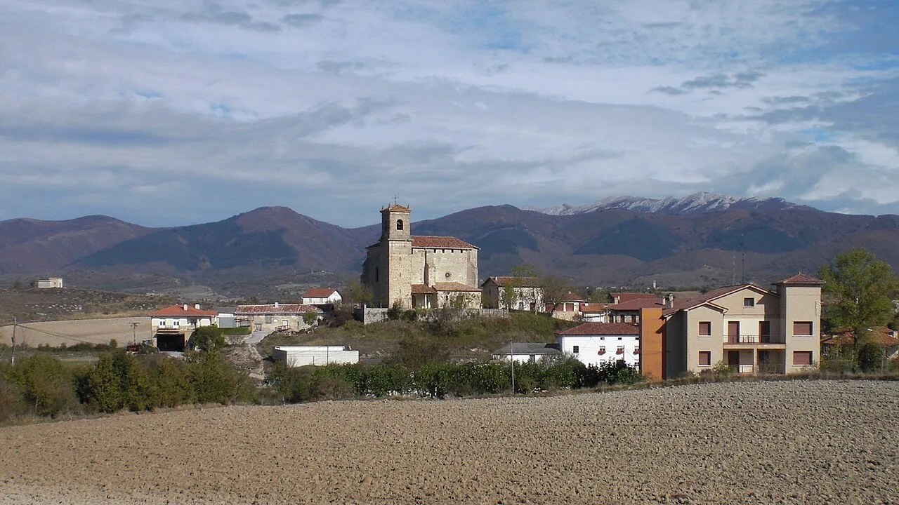 Kirche in San Millán mit Bergen und bewölktem Himmel.