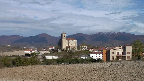 Kirche in San Millán mit Bergen und bewölktem Himmel.