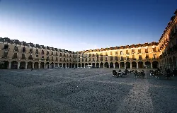 Large square with arcaded buildings and tables in the center in Ocaña.