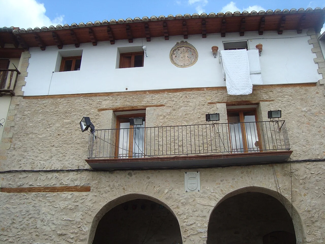 Stone building with balconies and arches on the ground floor.