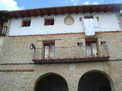 Edificio de piedra con balcones y arcos en la planta baja.