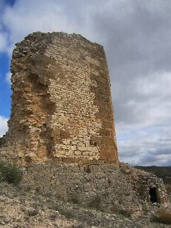 Ruinas de una torre de piedra en un paisaje árido con cielo nublado.