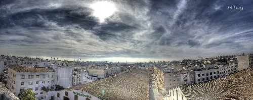 Panoramablick auf die Stadt mit Gebäuden und bewölktem Himmel.